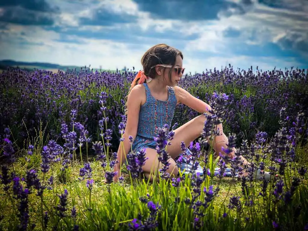 girl kneeling between lavender plants