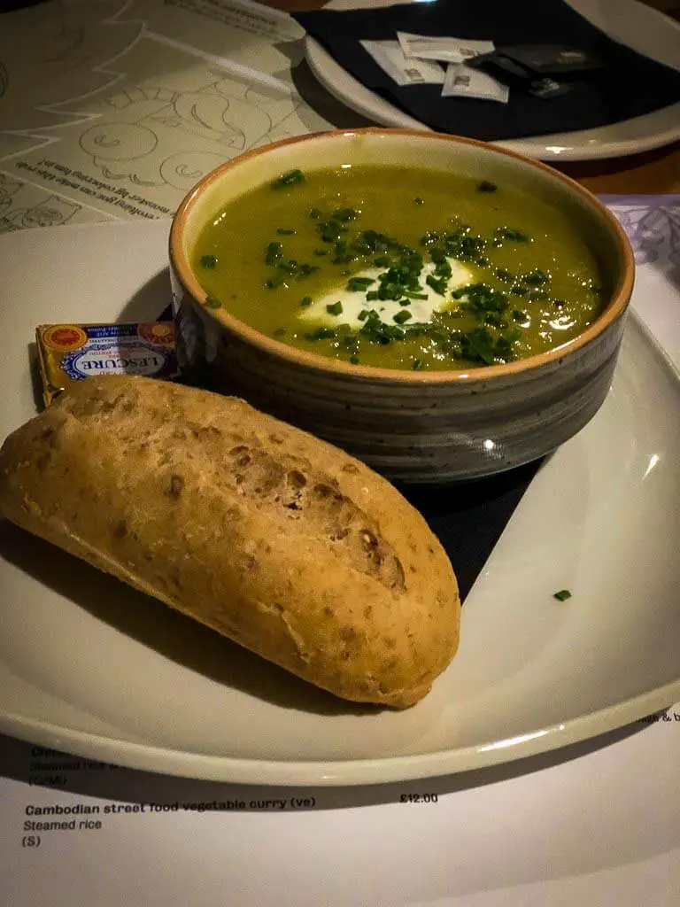 bowl of green soup with wholemeal bread roll