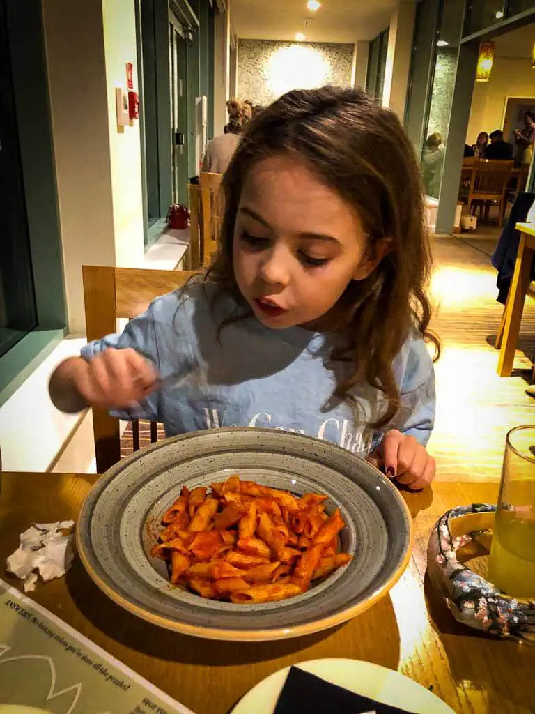 girl eating bowl of pasta and tomato sauce