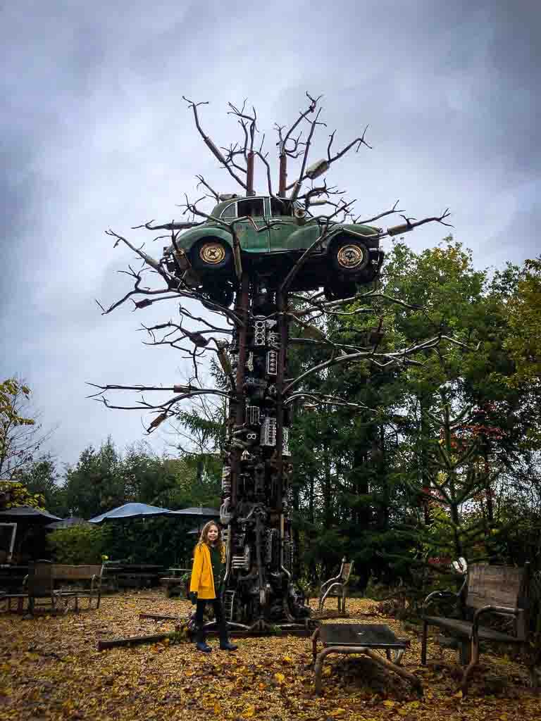 sculpture of scrap metal tree with a car stuck in the top
