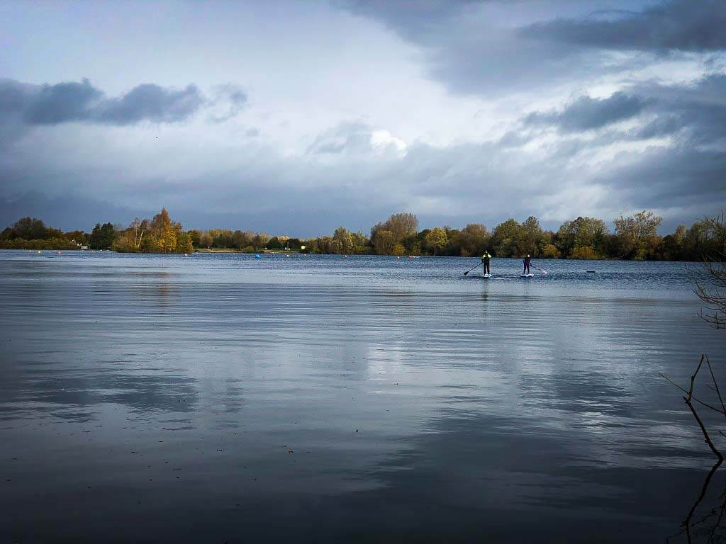 two people paddle boarding on a lake in the cotswolds