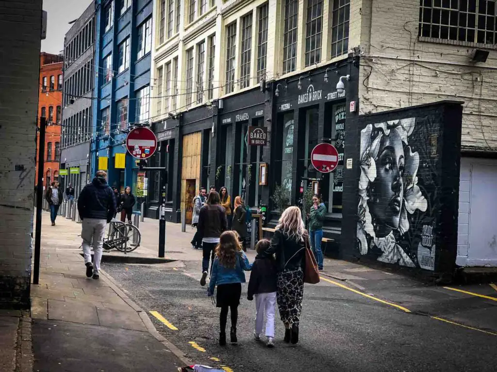 two young girls and their mum walking past a restaurant in Dogbeth, Birmingham