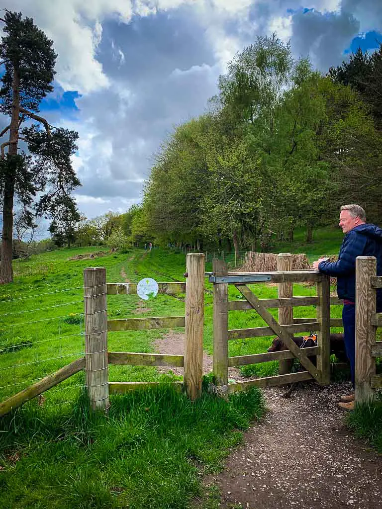 man in blue jacket going through a wooden kissing gate