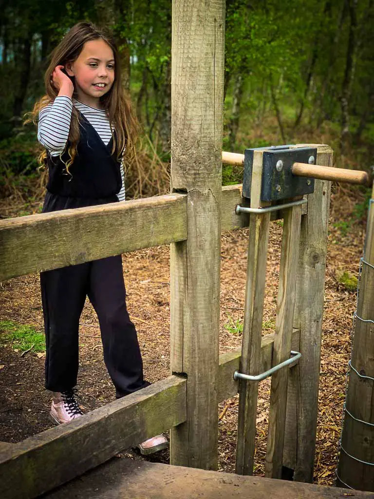 girl standing behind a dog gate at the trentham estate