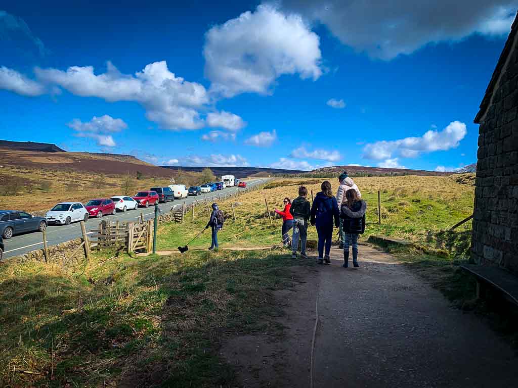 family crossing a road with car parked on the side to padley gorge