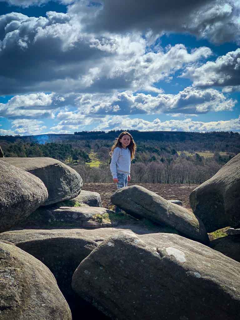 girl looking at camera standing on a big stack of rocks