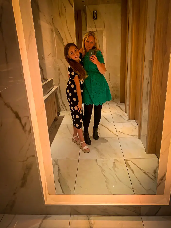 karen quinn in a green dress taking a selfie in a mirror with daughter piper quinn