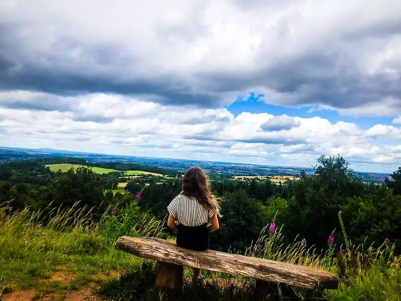 child sat on a wooden bench looking at views from a client hills walk