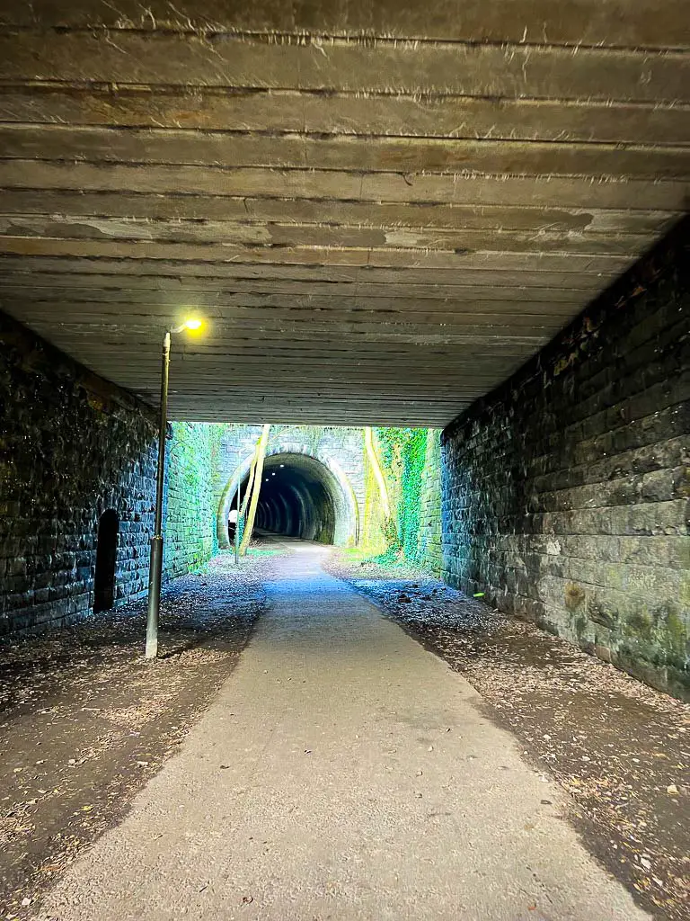 image being taken under a bridge towards the entrance of a tunnel